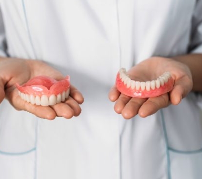 a doctor holding two different types of dentures sherman tx