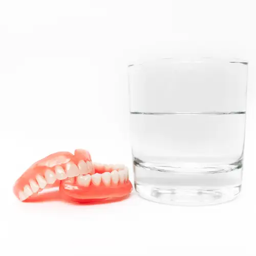 a full dentures Sherman TX  and a glass of water on a white background